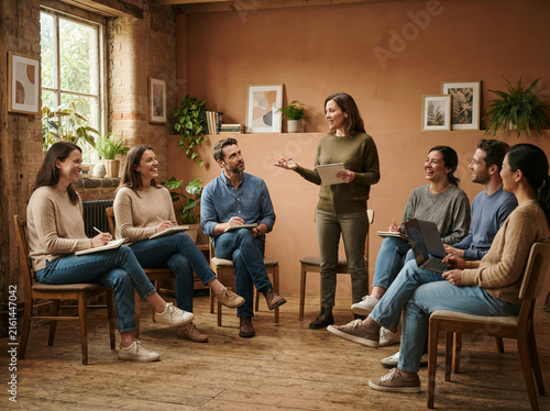 Team discussion circle with one standing presenter in a terracotta brick walled meeting room