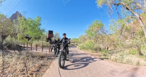 Scenic spring morning e-bike ride through Zion National Park in Utah, USA. Cyclists pedal along dramatic red rock canyons and green trails under soft morning light in this stunning national park lands