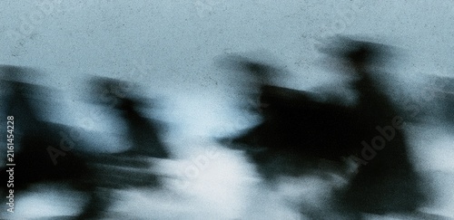 Silhouettes of figures blur in a monochromatic, atmospheric haze