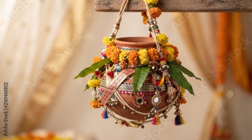 Traditional Dahi Handi decoration with hanging clay pot adorned with marigold flowers, leaves and colorful Indian ornaments.