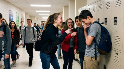 Teenagers laughing and talking in a school hallway beside lockers. Student friendship, peer interaction, social behavior, and everyday secondary education life.