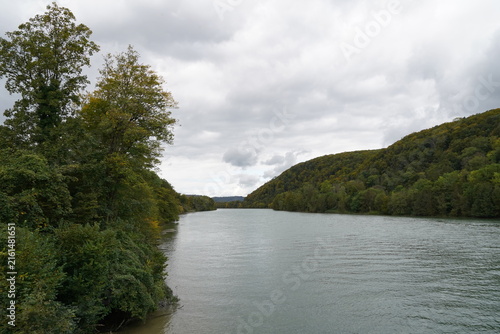 Calm Rhine river flowing through Swiss forested hills.