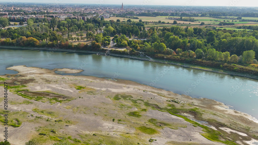 Obraz premium Po River experiencing critical low water levels during 2026 heatwave drought, revealing extensive sand banks near Cremona, symbolizing climate change and water crisis