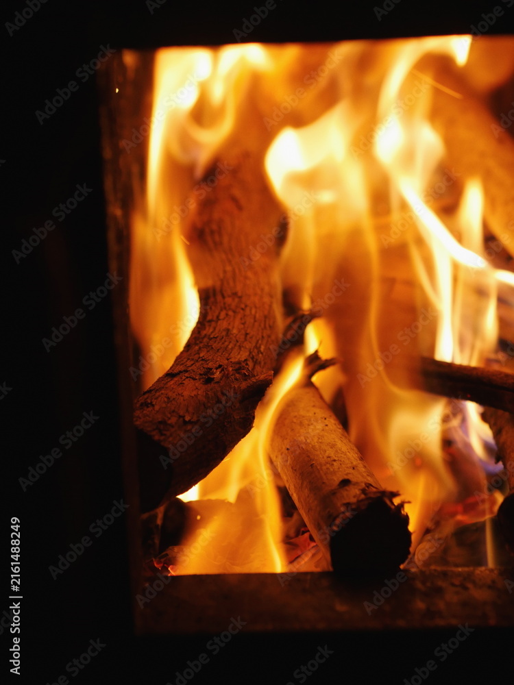 Fototapeta premium Fire is burning in a fireplace, with the flames reaching up to the ceiling