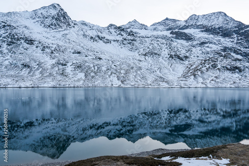 Konstfotografi Snow-capped mountains mirror perfectly in calm, deep blue water