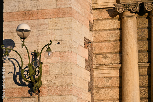 Ornate street lamp and classical column in warm sunlight in Verona