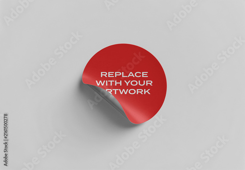Circular sticker mockup with peelable corner on neutral gray surface for branding and graphic design presentation, template product packaging promotional artwork display