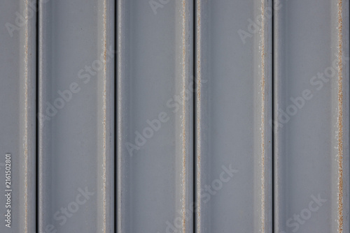 close-up, full-frame shot of a gray corrugated metal sheet with a row of rusty bolts.