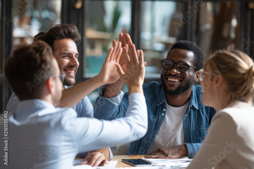 Happy business team giving high five after successful meeting