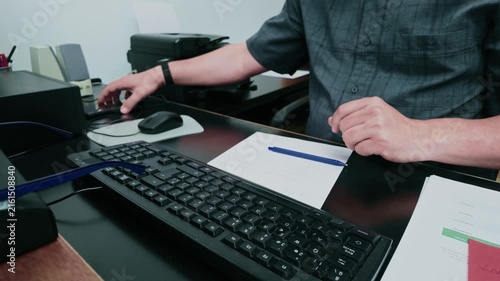 Busy male employee writing notes and using smartphone at office desk