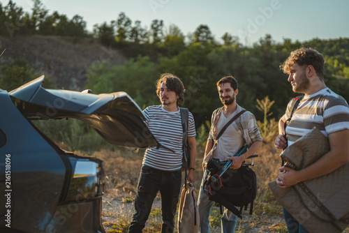 Friends packing camping gear into car trunk for road trip