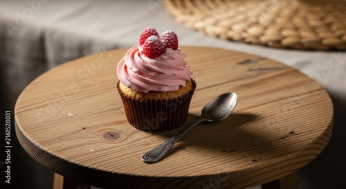 Sweet raspberry cupcake with pink frosting and fresh berries, served with spoon.