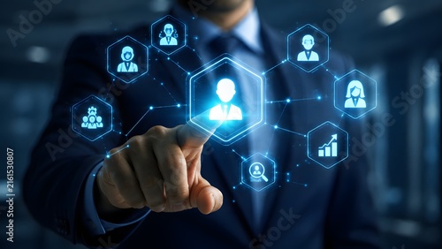 A professional businessman interacting with a digital holographic image showing human resource management icons and networking connections in a modern office environment