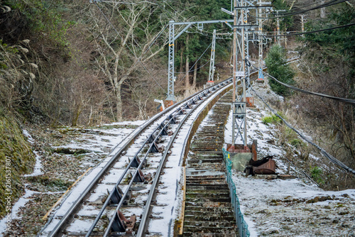 Quadro su tela Funicular railway track crossing steel bridge frame on wooded mountain slope at