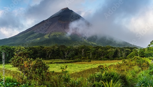 lush green landscape surrounds arenal volcano s cone shaped peak misty clouds linger mist landscape