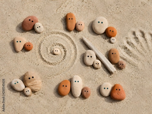 Cute painted pebble family figures arranged on sandy beach