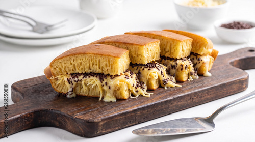 Indonesian sweet martabak pancake stuffed with melted cheese and chocolate sprinkles on wooden board