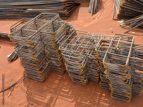 Fotografía Stack of rusted concrete reinforcing steel bars lying on red dirt, ready to use, raw building material ready for foundation work