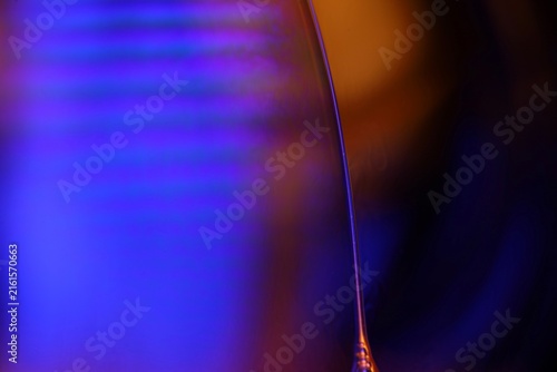 Glowing blue liquid film boundary with striped interference and warm amber bokeh. Electric blue and purple backlighting illuminates a vertical fluid membrane boundary featuring soft horiz