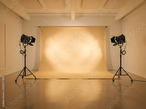 Professional photography studio with beige backdrop and studio lighting equipment setup