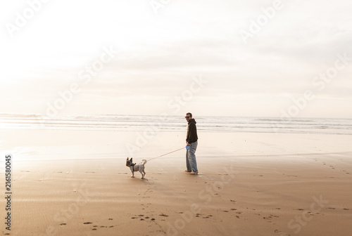 Man walking dog on the beach during summer