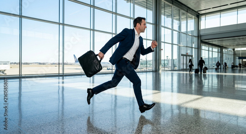 Businessman in Navy Suit Running Through Airport Terminal with Briefcase