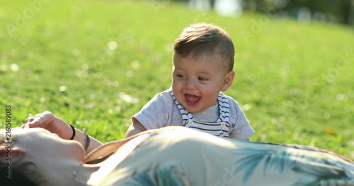 Картината върху платно Baby and mother together laid on grass outside at park smiling relationship