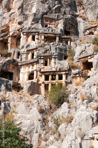Vertical close-up of ancient Lycian rock-cut tombs carved into the sheer cliffside in the ruins of Myra ancient city in Demre, Turkey