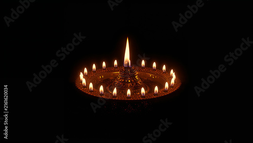 Traditional metal lamp with multiple burning flames isolated on a dark black background ceremony tradition spiritual religion hinduism festival illumination meditation devotion blessing