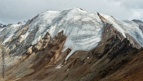 Molodezhny Glacier viewed from Molodezhny Peak near Almaty, Kazakhstan, in August, with the surrounding mountain range and Tuyuk-Su Glacier visible in the background.
