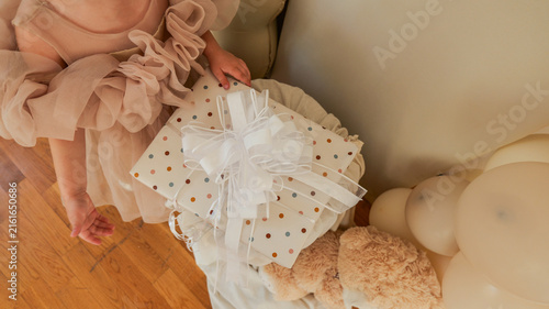 Foto A child in a frilly dress reaches for a polka dot gift box with a white bow