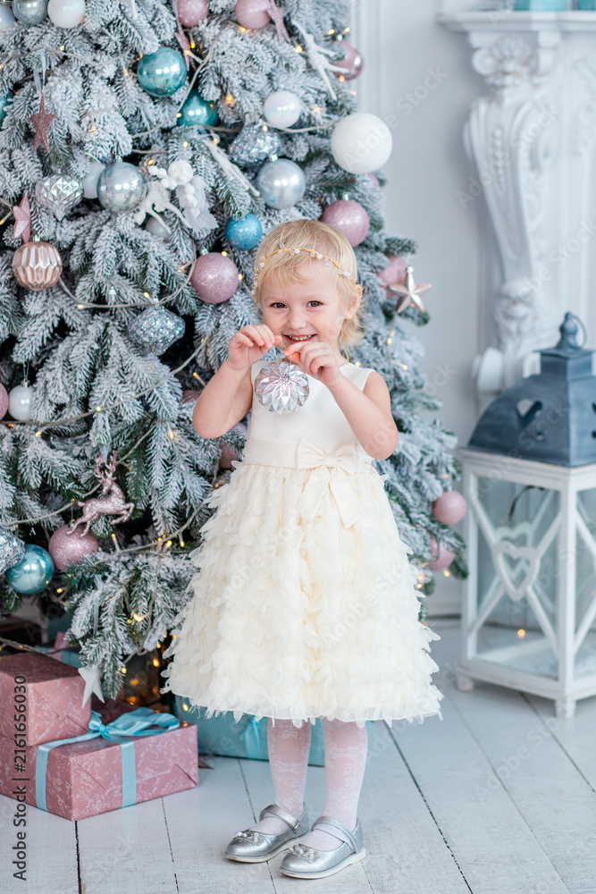 Fototapeta premium Child holds ornament by Christmas tree in winter