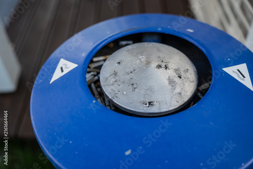 Foto Public designated smoking area outdoor blue metal ashtray bin filled with discar