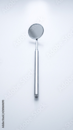 Single Dental Mirror Standing Upright on White Surface, Studio Shot