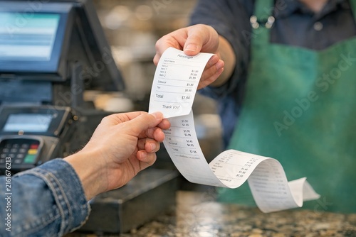 A person hands a receipt to another, likely completing a transaction