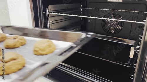 Woman hands taking baked chocolate cookies out of oven close up 16:9, homemade bakery concept