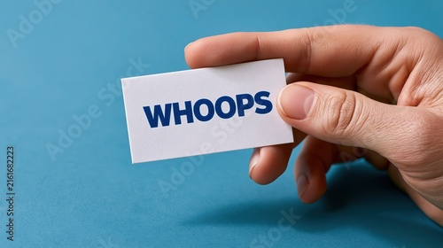 Human hand holding white rectangular card with blue whoops text