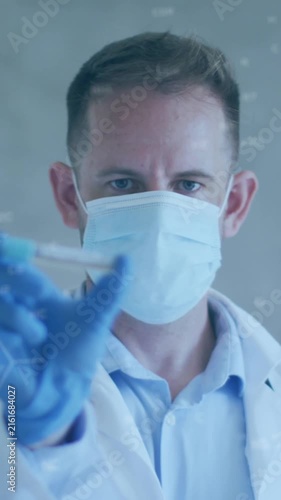 Animation of chemical structures over caucasian male doctor holding vaccine wearing face mask