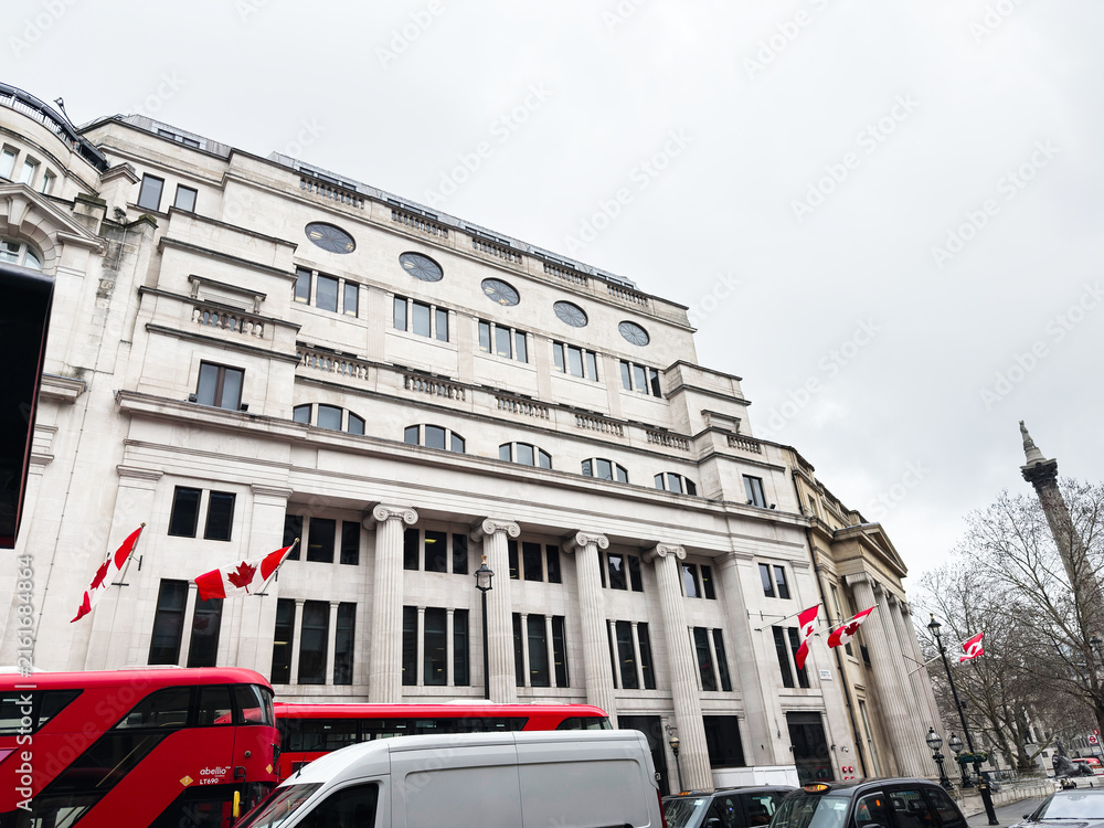 Fototapeta premium Historic stone office Oceanic House building with Canadian flags and red buses on a London, UK Cockspur street