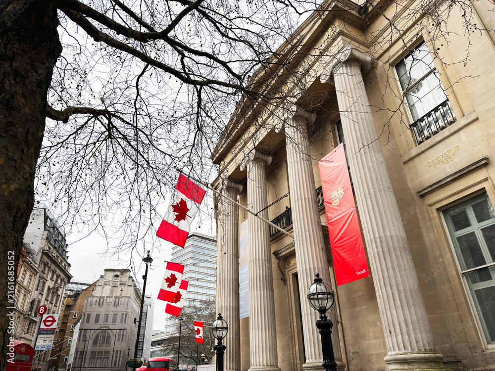 Fototapeta premium Canadian flags fluttering outside a classical building on Cockspur Street in London, UK, near Trafalgar Square