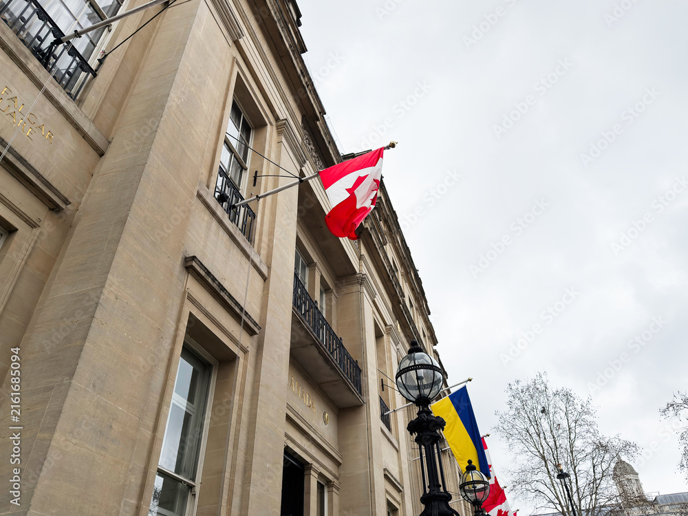 Fototapeta premium Canadian and ukrainian flag flying from a historic government building facade in London, UK alongside other national flags