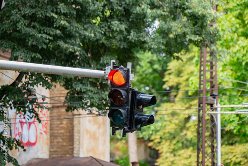 Red traffic light signal showing a stop indication at an urban intersection with a bright illuminated lamp shining during daytime hours