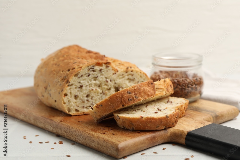 Naklejka premium Fresh bread with flax seeds on white table, closeup