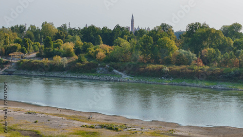 фотографія Po river flowing past a green riverbank with Cremona's Torrazzo tower and Duomo