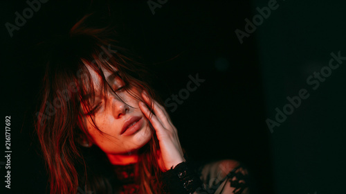 redlit intimate portrait of a thoughtful brunette woman, dramatic monochromatic portrait of a pensive brunette in deep red light, mysterious closeup of a woman lost in thought