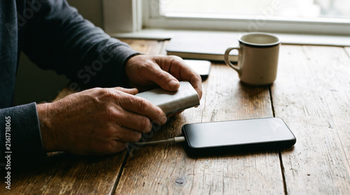 Person connecting a mobile phone to a power bank to charge the battery.
