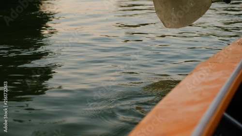 Close-up of paddle dipping into water and splashing during kayak row.