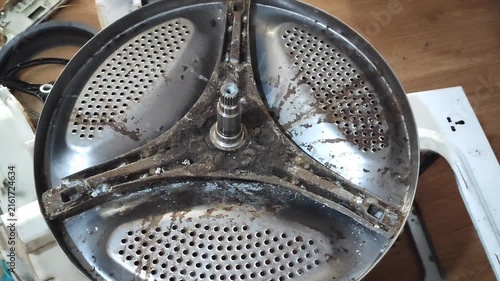  Dirty washing machine drum interior with perforated metal tub showing residue buildup, requiring cleaning and maintenance.