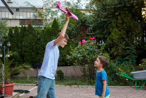 Cuadro en lienzo Teenage brother playing outdoors with his younger brother, holding a colorful pi