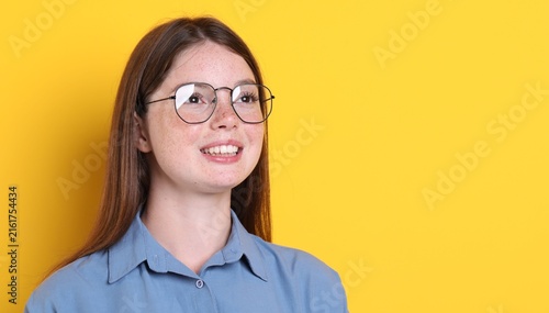 Obraz na płótnie Beautiful girl with freckles wearing glasses on orange background, space for tex
